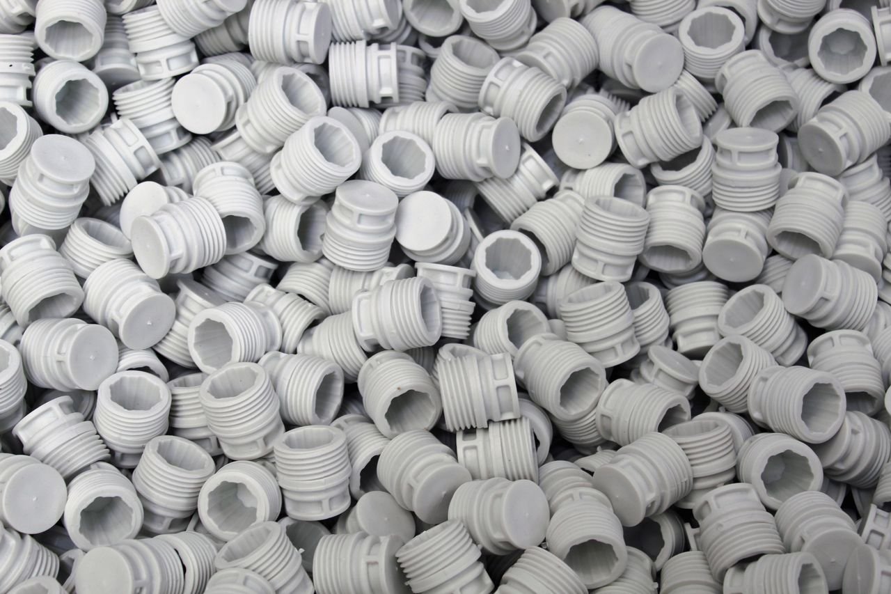 Services A high-quality image of numerous white plastic screw caps piled together, showcasing industry production.
