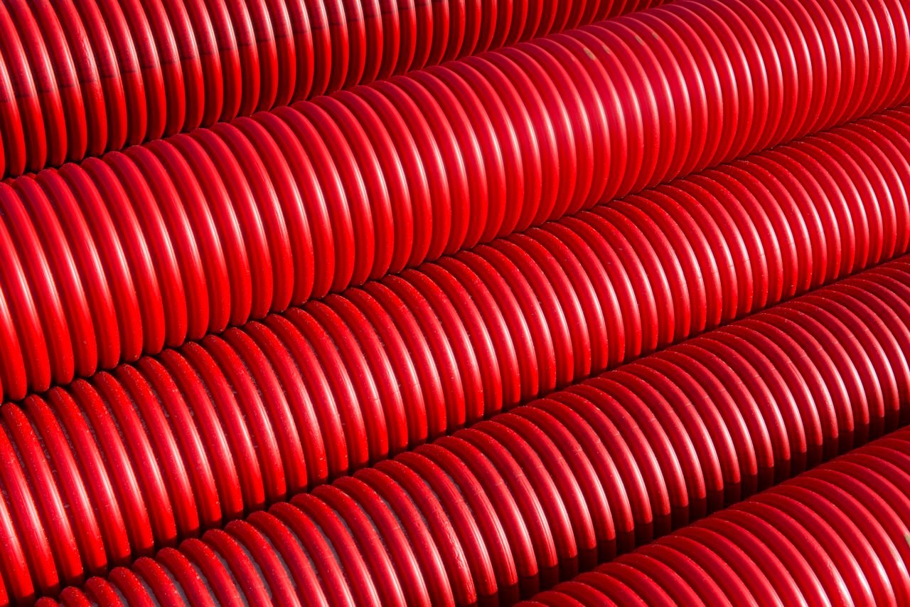 Services Bright red pipes aligned in a geometrical pattern, capturing light reflections in a close-up shot.